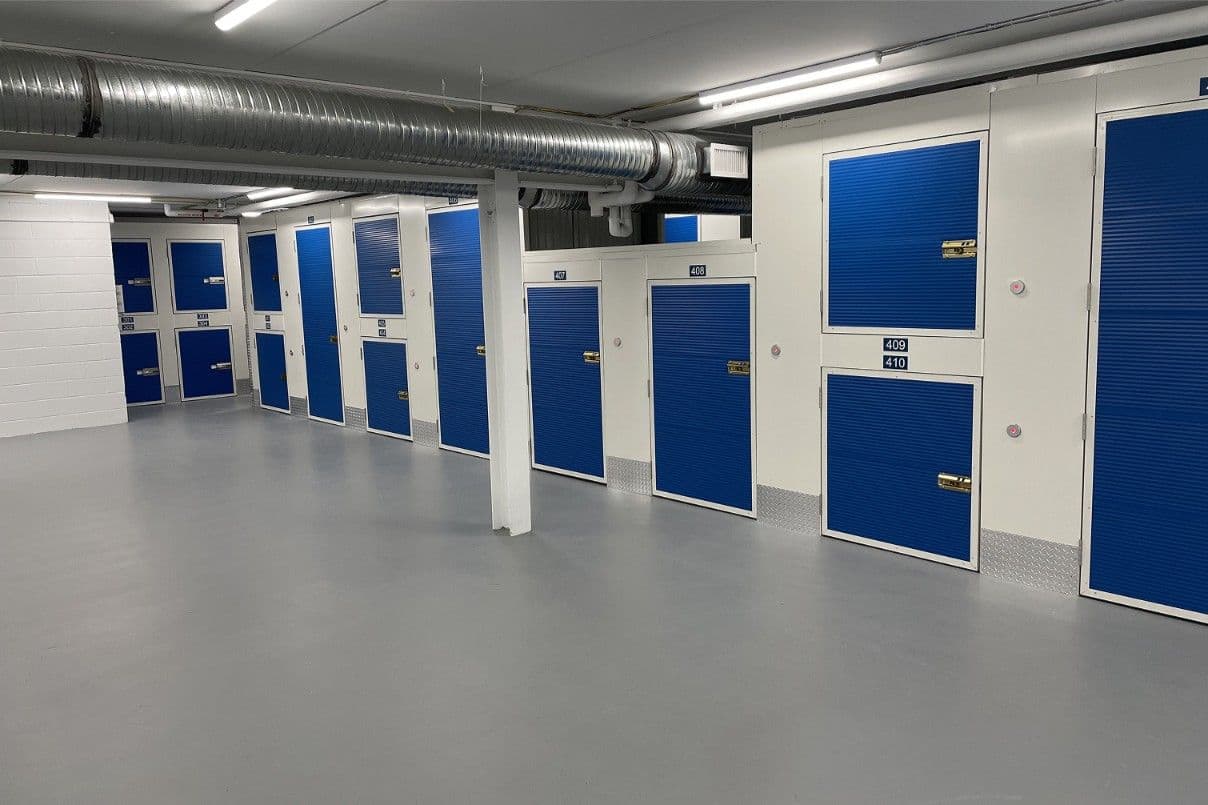 Storage units with blue doors on the bright basement level at CityBox Midtown